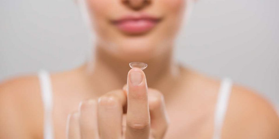 focus on contact lens on finger of young woman young woman holding contact lens on finger in front of her face woman hold...