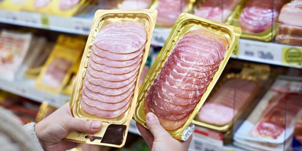 woman chooses a slice of ham and meat in vacuum package at the grocery store