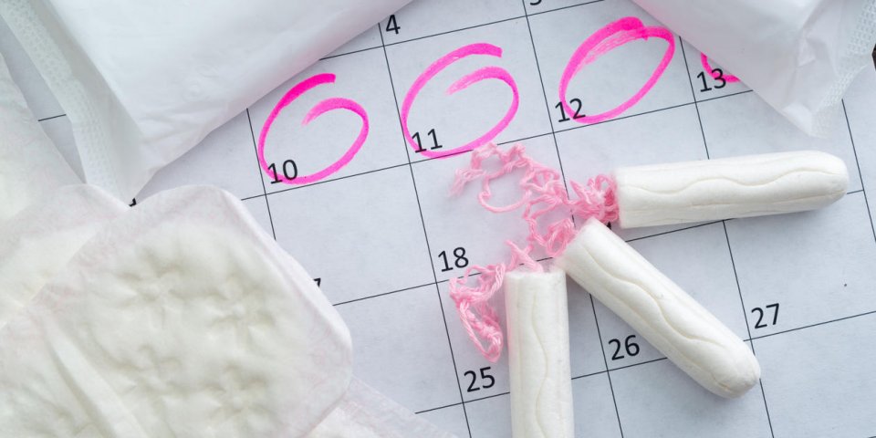 calendrier blanc avec cercles roses autour de la date de la menstruation et tampons propres sur le dessus