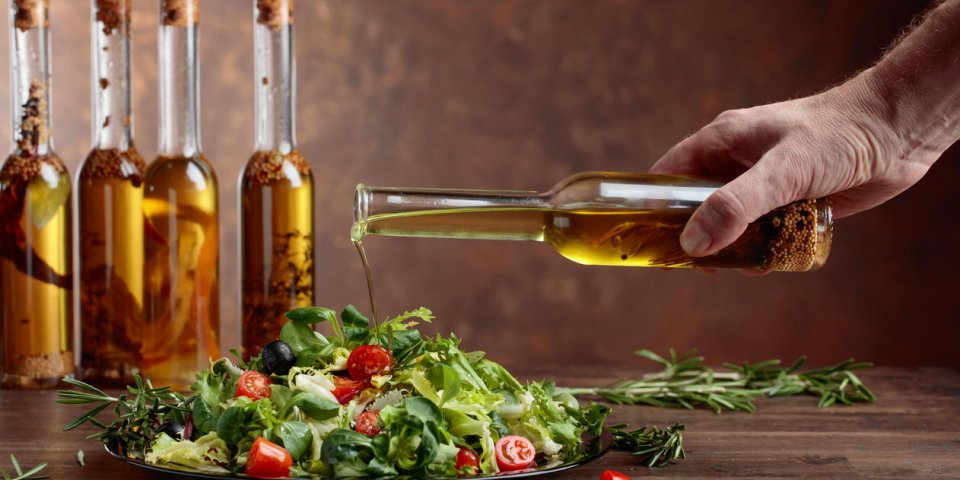 vegetable salad with olive oil pouring from a small bottle old wooden table and brown background copy space