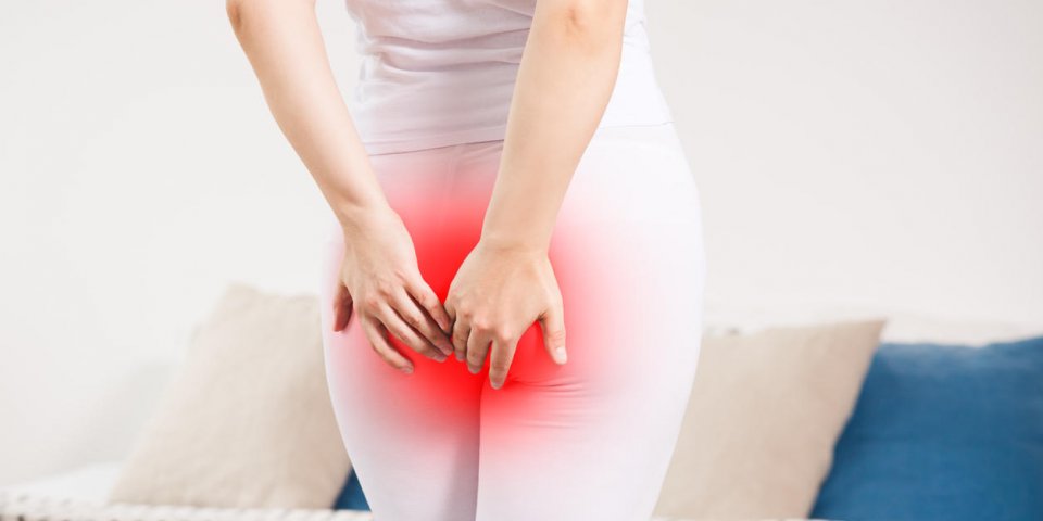woman suffering from hemorrhoids at home, anal pain, painful area highlighted in red