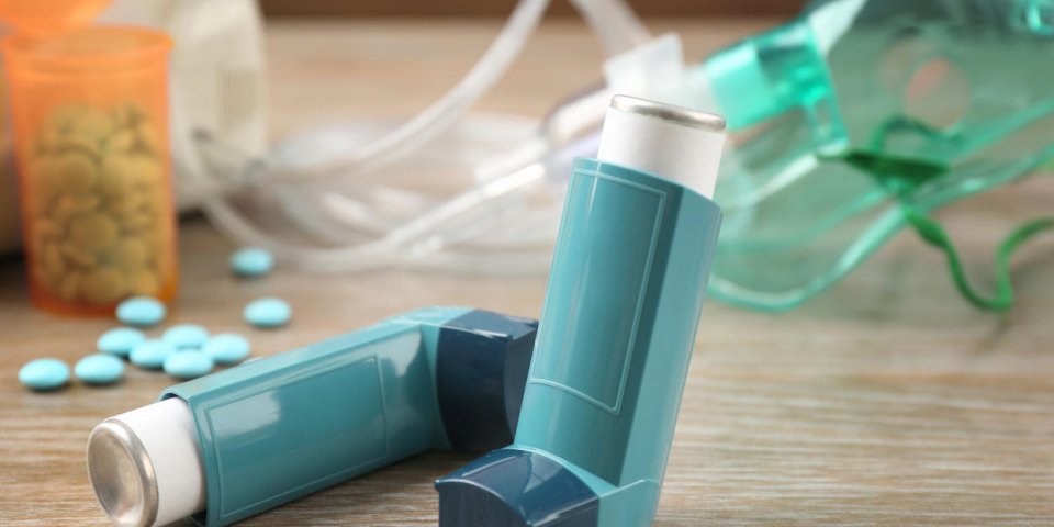 asthma inhaler, pills and nebuliser on wooden table