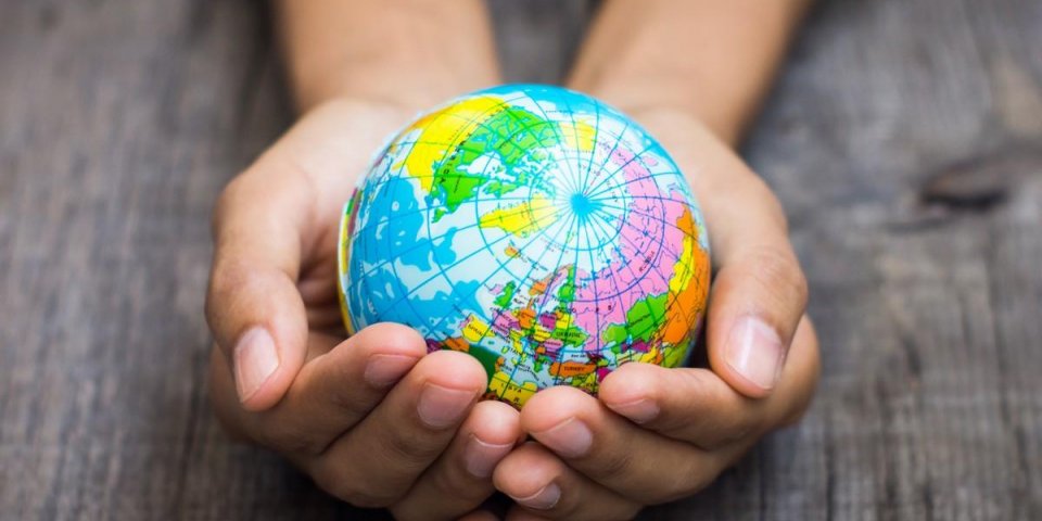 a person holding a globe on wooden background