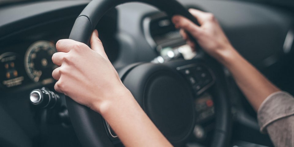 close-up of female hands on steering wheel while driving a car