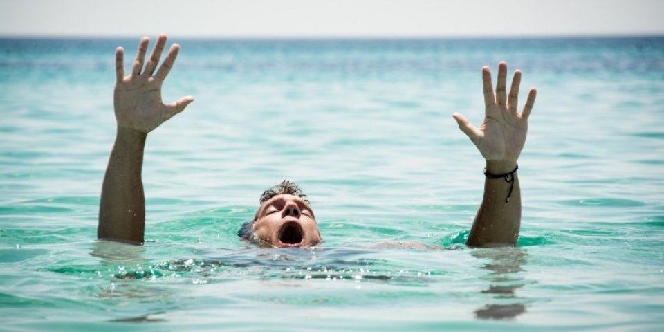 drowning man in sea asking for help with raised arms