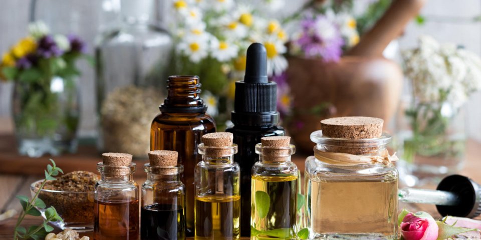 selection of essential oils with various herbs and flowers in the background