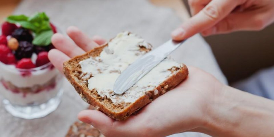femme main frotte le beurre sur un morceau de pain de seigle