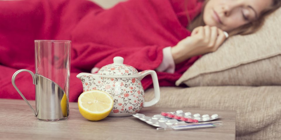 femme malade recouverte d'une couverture couchée dans son lit avec une forte fièvre et une grippe, théière au repos, ...