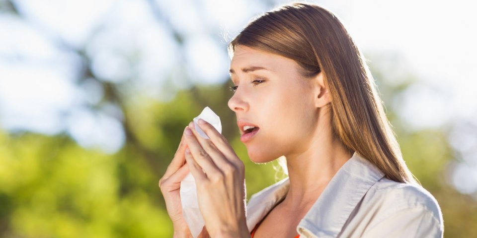 beautiful woman using tissue while sneezing in park