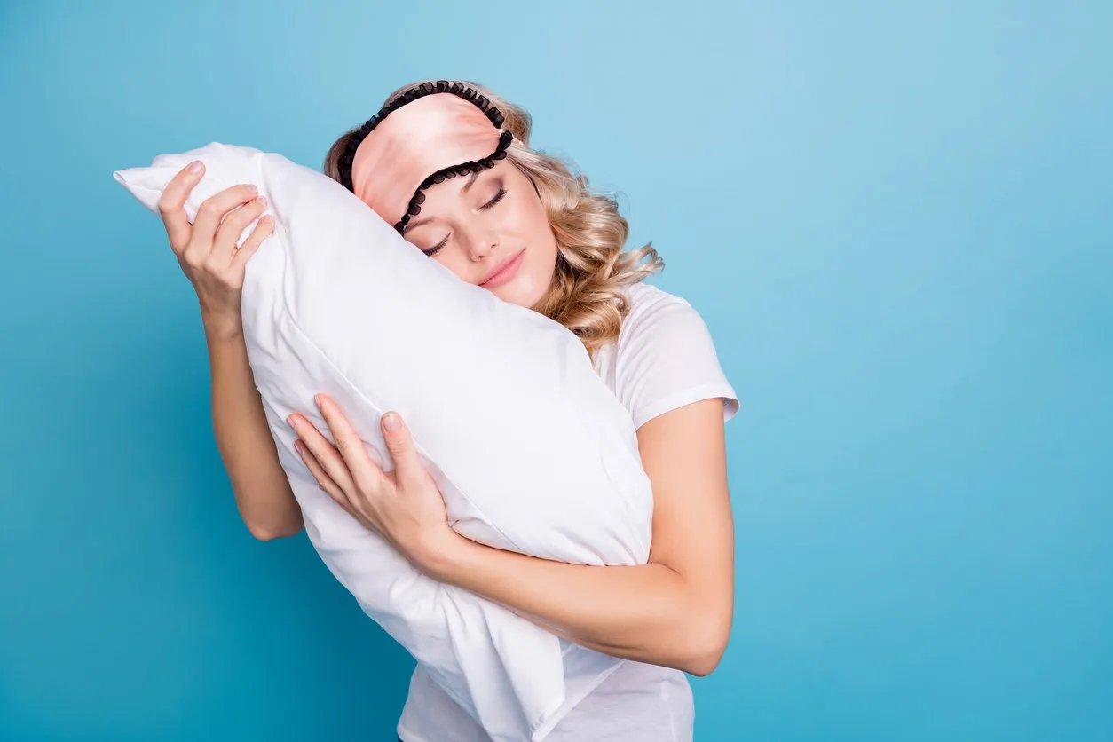 close up photo beautiful funky her she lady hands arms palms hold cuddle big large pillow careless expression glad day off wear sleeping pink mask casual white t-shirt clothes isolated blue background