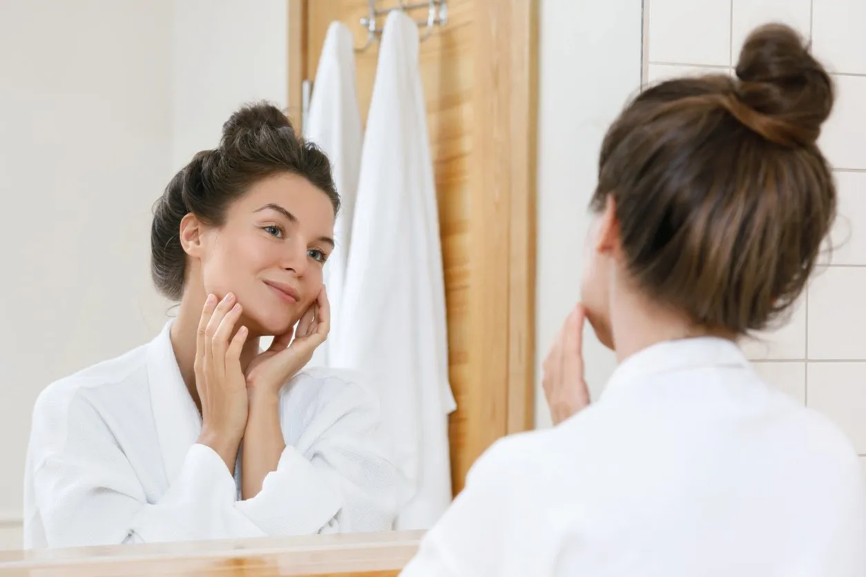 young woman is looking into the mirror at morning