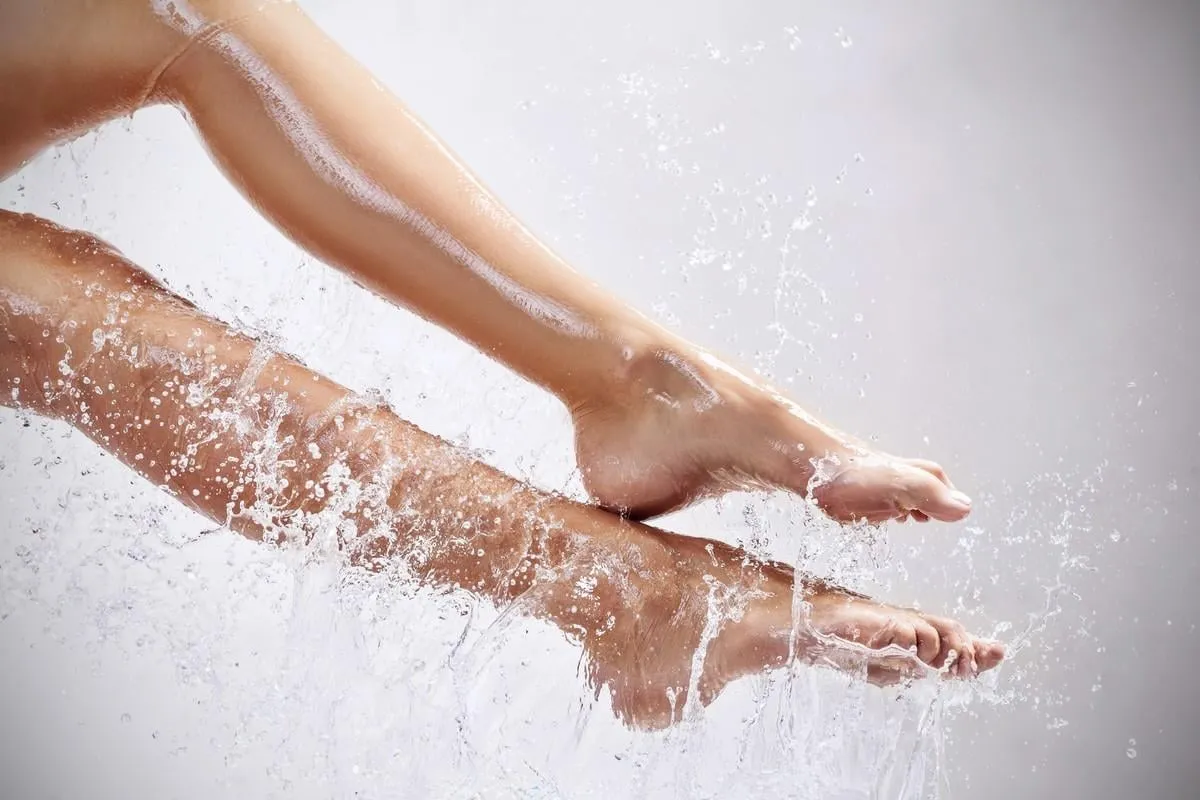 sensual woman's legs in clean water splashes over gray background