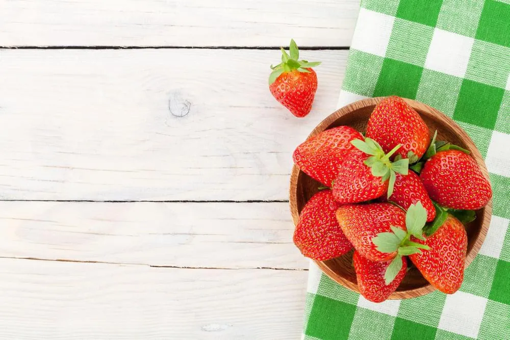 fraise mûre fraîche dans un bol sur le fond de la table en bois vue de dessus avec l'espace copie