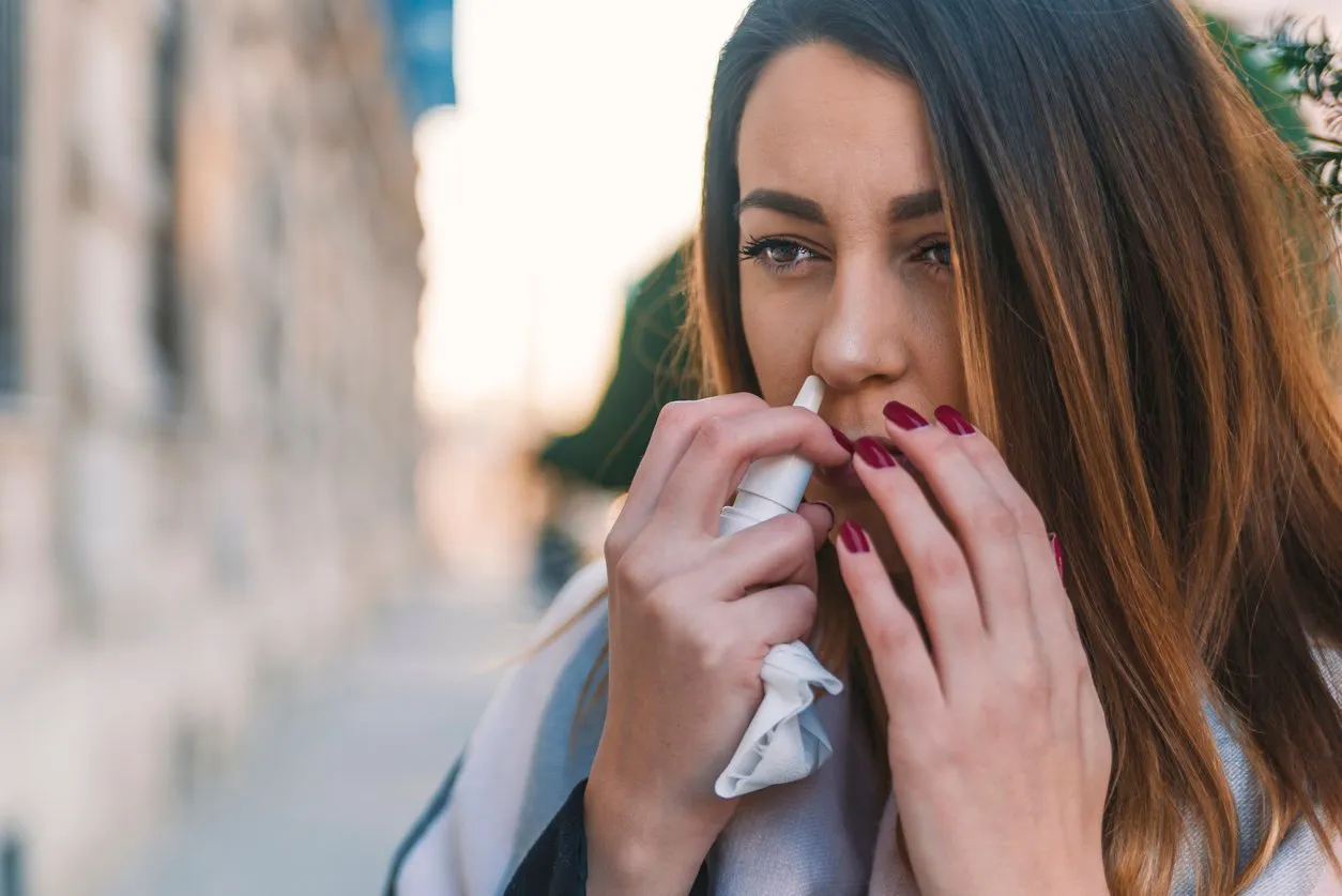 woman is having flu and she is using nasal spray to help herself woman using nasal spray nasal spray to help a cold sick with a rhinitis woman dripping nose woman applies nasal spray