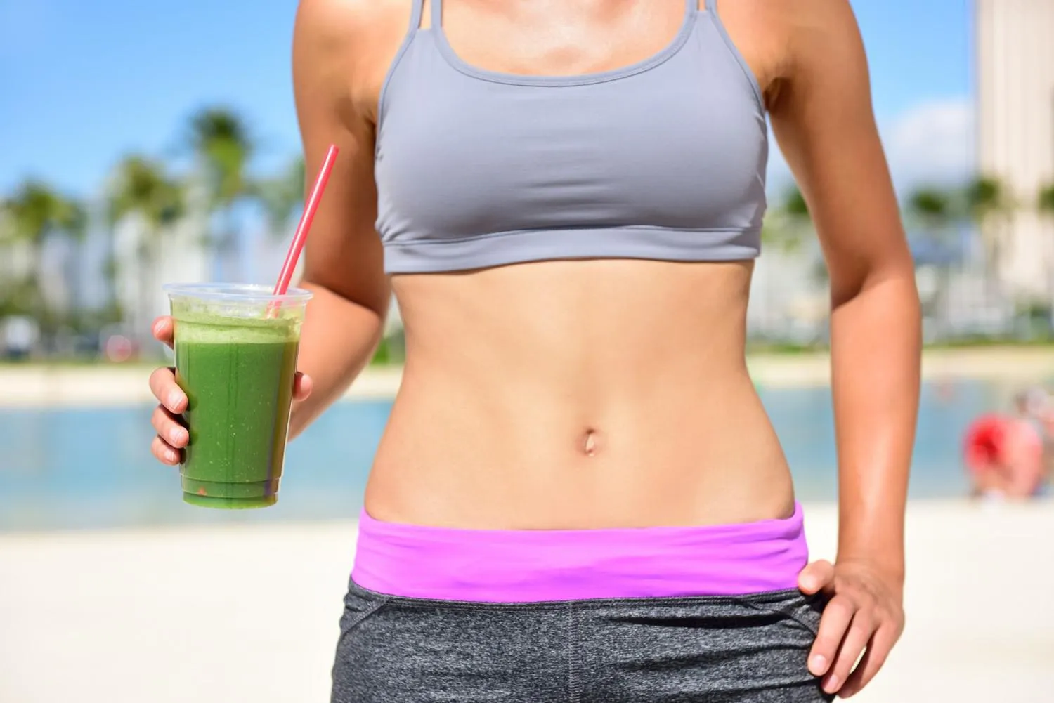 femme de remise en forme de mode de vie sain boire du jus de smoothie de légume vert après l'exécution de l'exercice bouchent de smoothie et de l'estomac concept de mode de vie sain avec ajustement modèle féminin à l'extérieur sur la plage