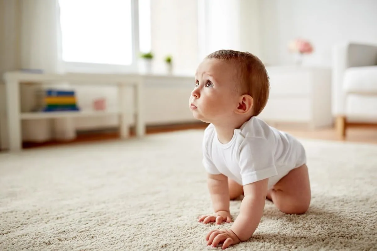 childhood, babyhood and people concept - little baby boy or girl crawling on floor at home