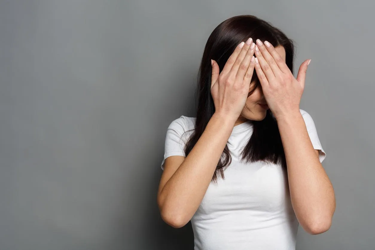 see no evil concept portrait of young scared woman covering eyes with hands while standing against gray studio background confused girl close eyes with palms ignoring something