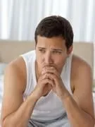 homme pensif ayant un mal de tête assis sur le lit avec sa petite amie sur le fond