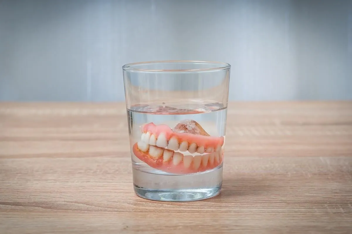 false teeth swim in transparent water glass - dental concept