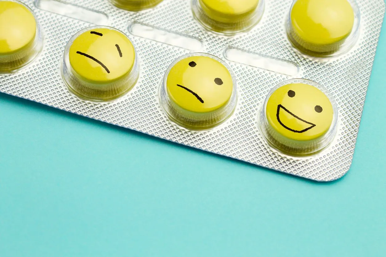 yellow pills andfunny faces in a blister on a blue background