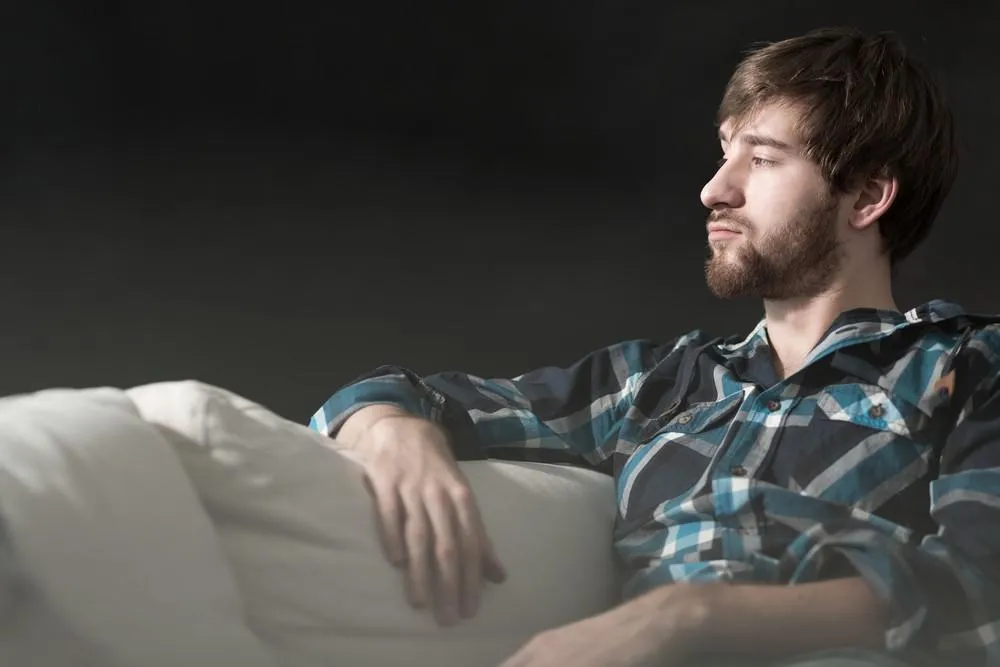 jeune homme déprimé est assis sur le canapé