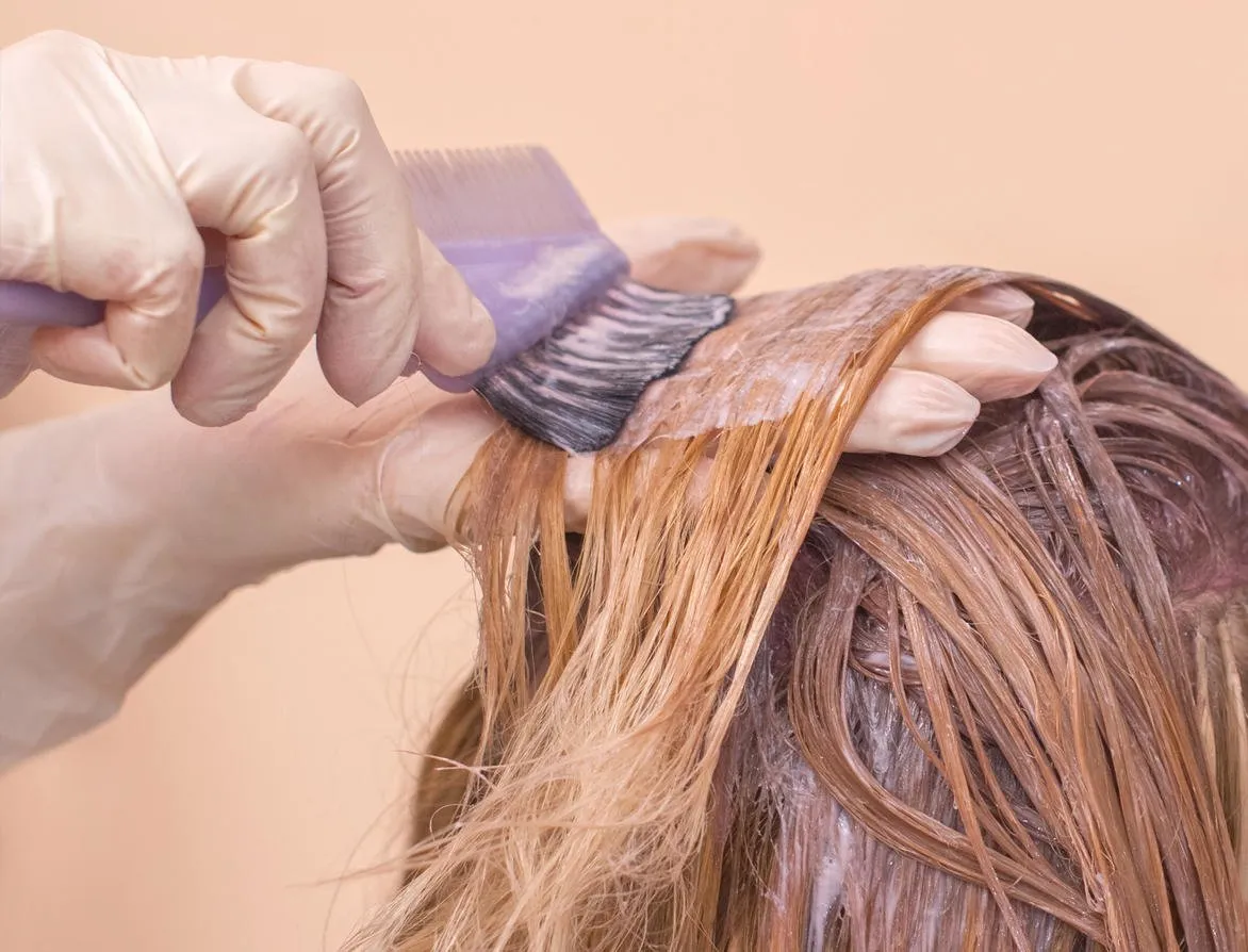 the hairdresser paints the woman's hair in white, apply the paint to her hair in the beauty salon