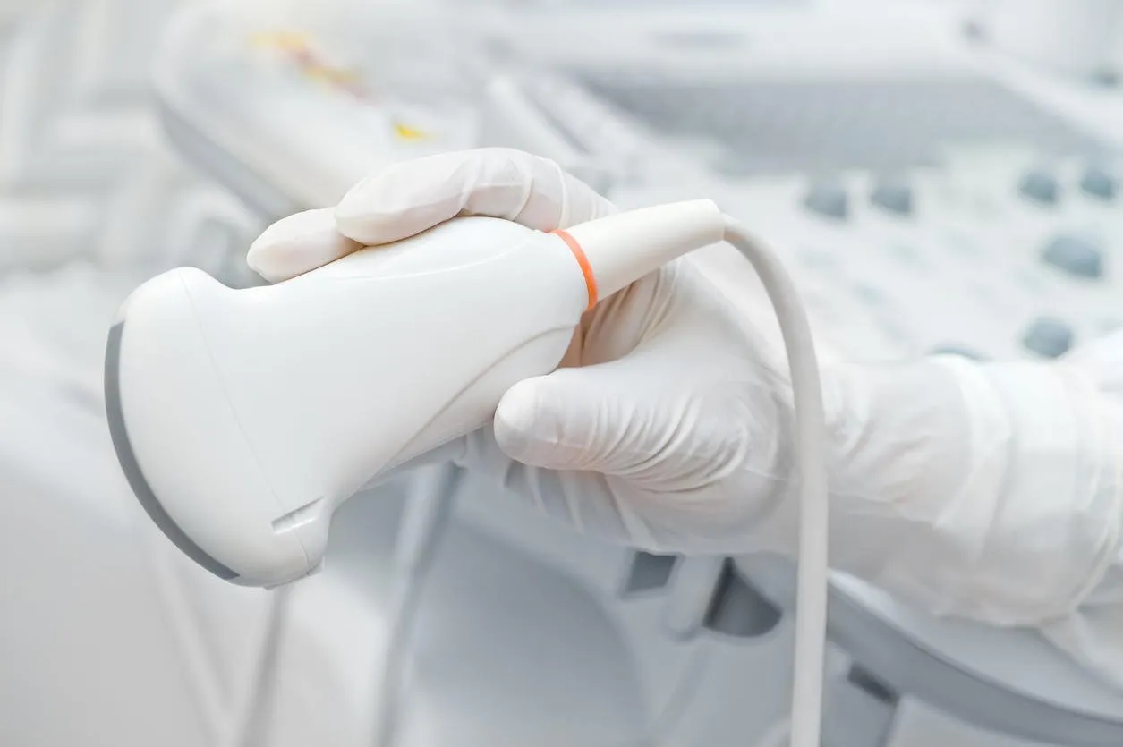 close-up of white gloved hand holding ultrasound device