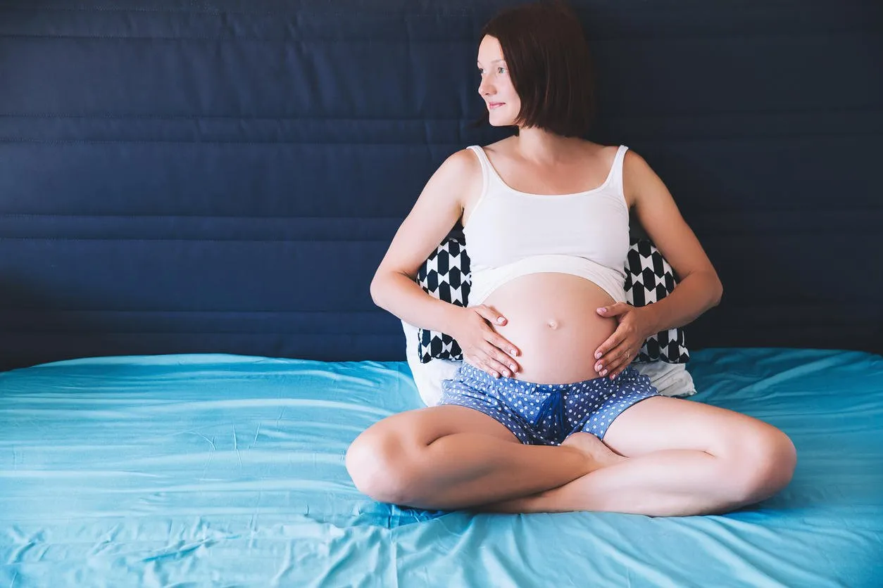 beautiful pregnant woman holds hands on belly in bedroom at home young mother waiting of a baby concept of pregnancy, maternity, health care, gynecology, medicine close-up, indoors
