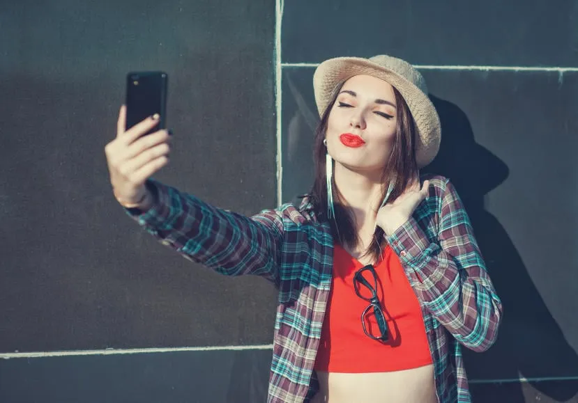 belle jeune fille au chapeau prenant la photo d'elle-même, selfie