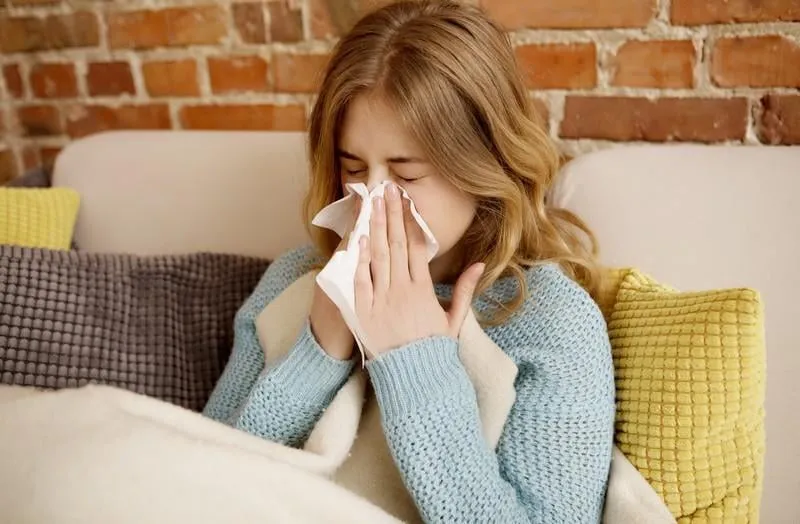 young ill woman sitting on sofa, she is having cold or flu