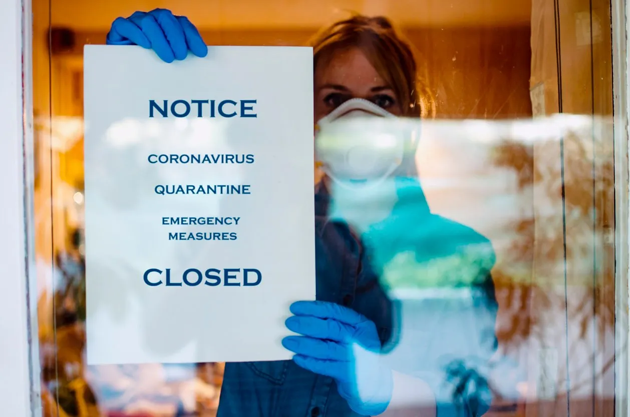 woman with notice paper warning text of coronavirus on window glass indoorsclosed in home self isolation due to covid-19 infection desease