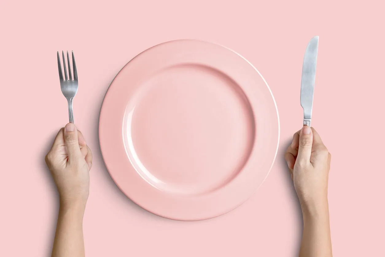 dinner place setting a pink plate with silver fork and knife isolated on pink background with clipping path