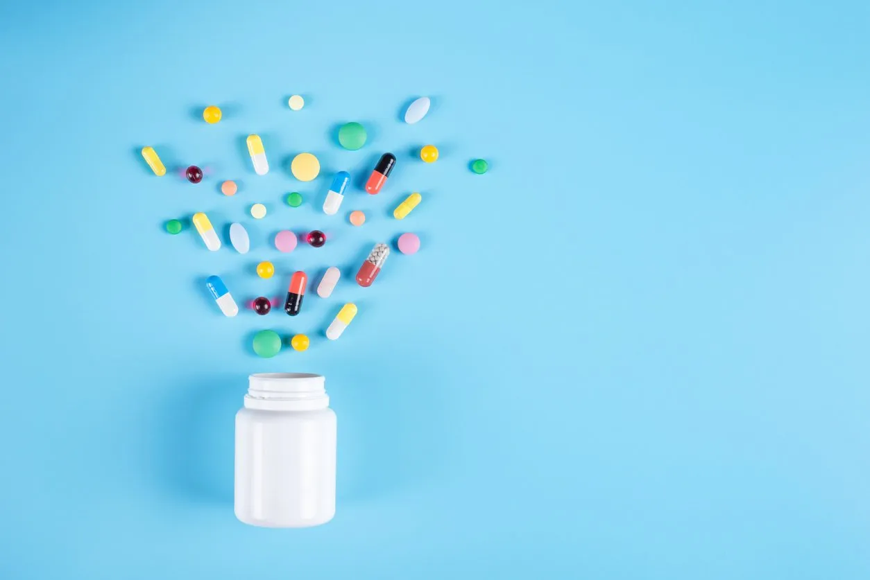 assorted pharmaceutical medicine pills, tablets and white bottle on blue background copy space for text