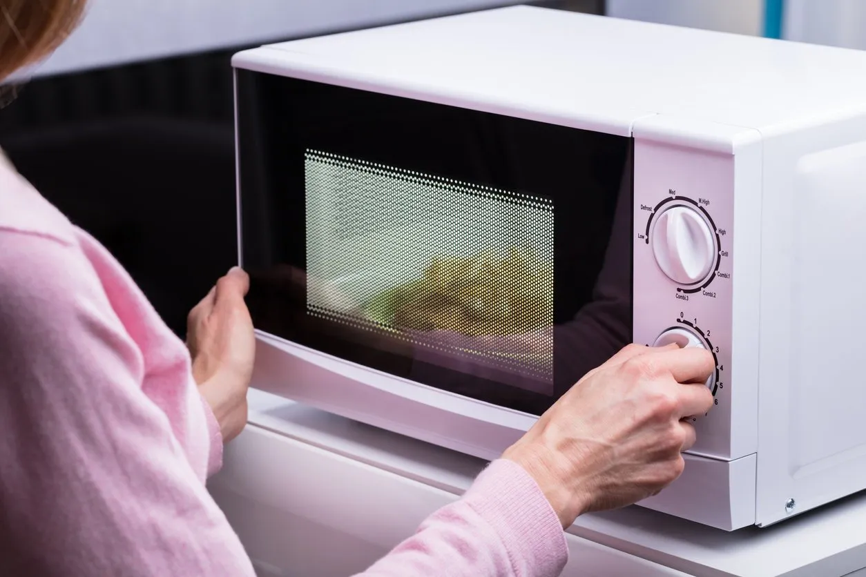 close-up of woman using microwave oven for heating food at home