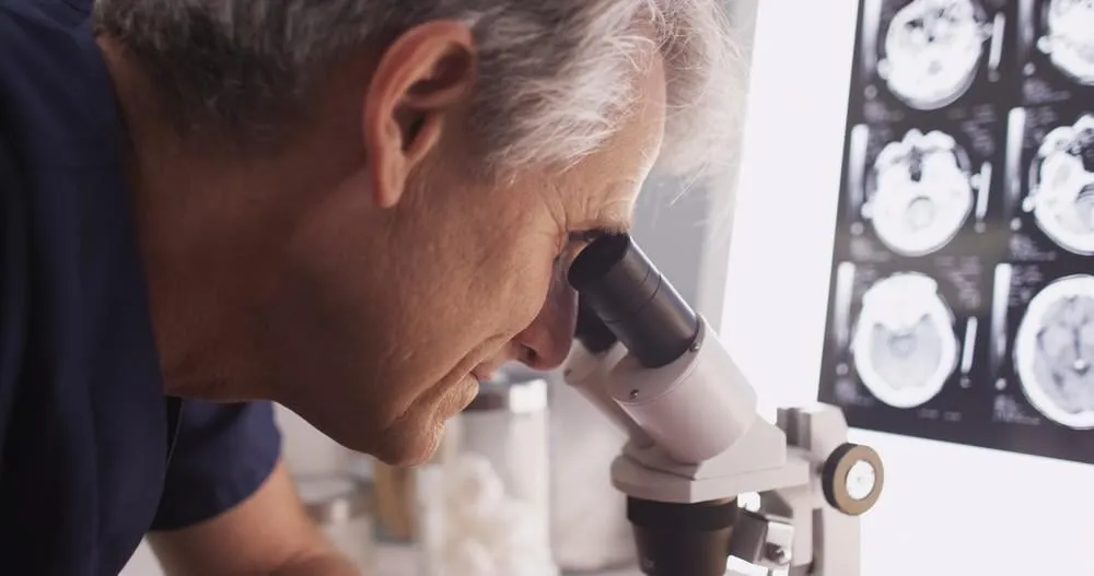 docteur âgé moyen intelligent à la recherche dans le microscope