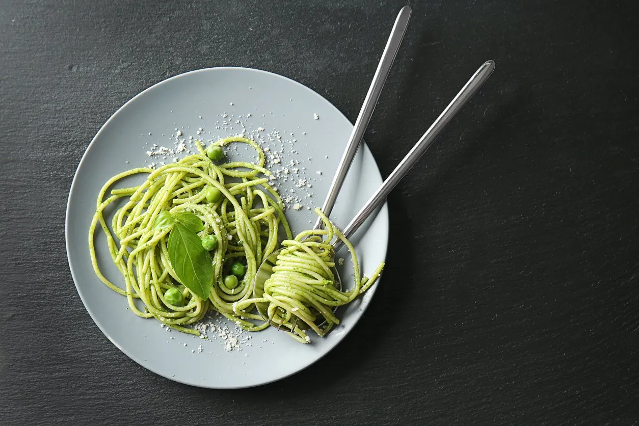plate with tasty pesto pasta on dark background