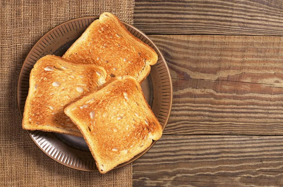 slices of toasted bread in plate on wooden table, top view space for text