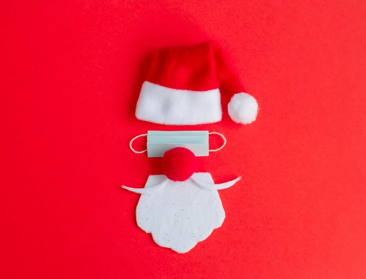 santa claus hat and beard with face mask on a red background, creative minimal concept of christmas and new year