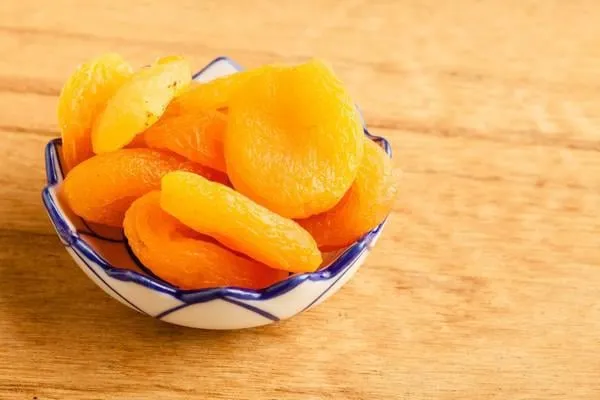 bol de régime de nutrition saine d'abricots secs sur fond de table en bois