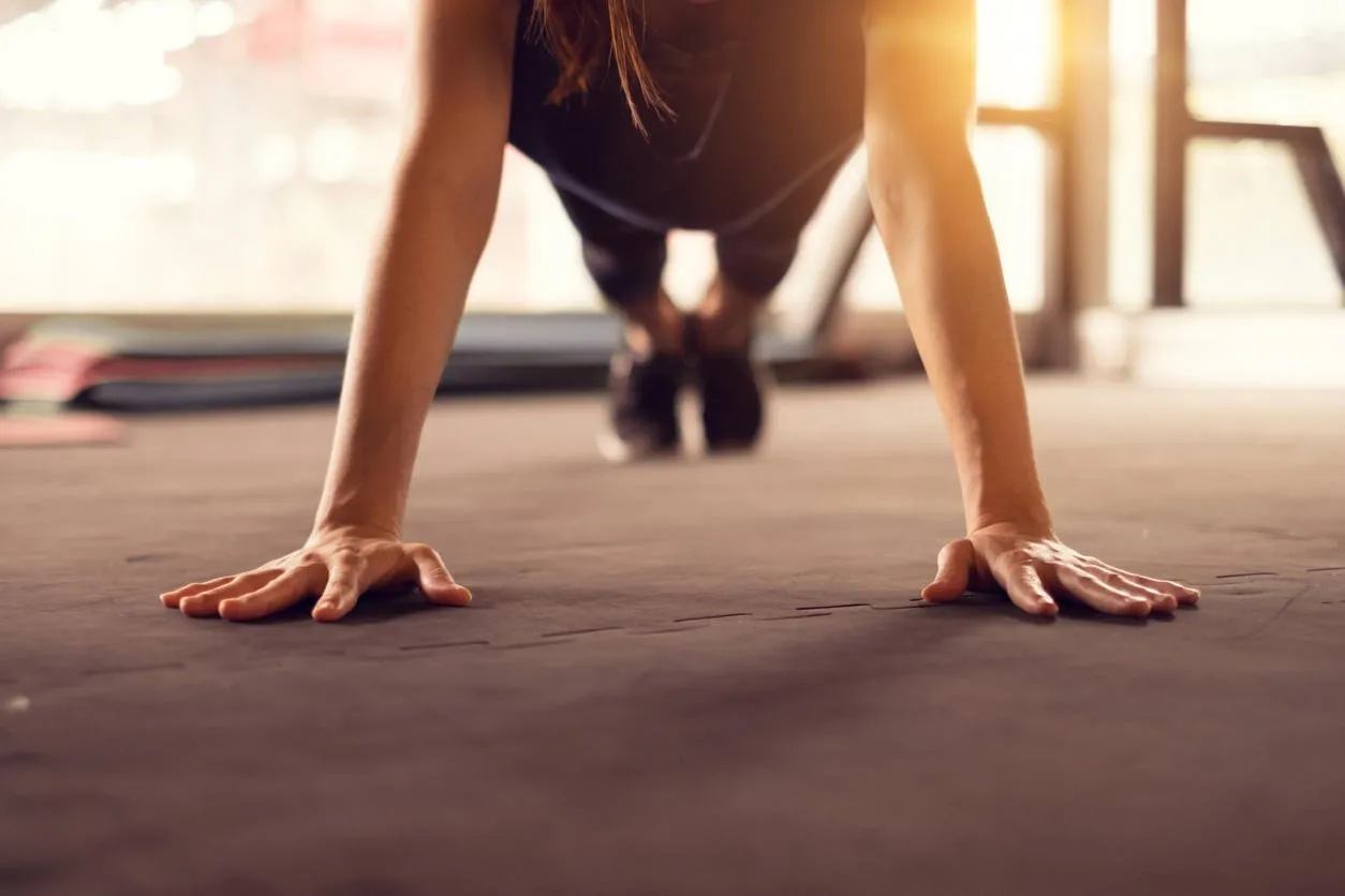 close up woman hand doing push ups exercise in a gym in morning, sunlight effect