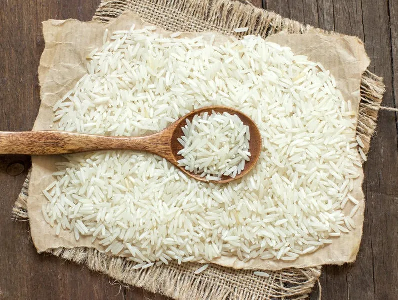 riz basmati avec une cuillère sur un bois sombre