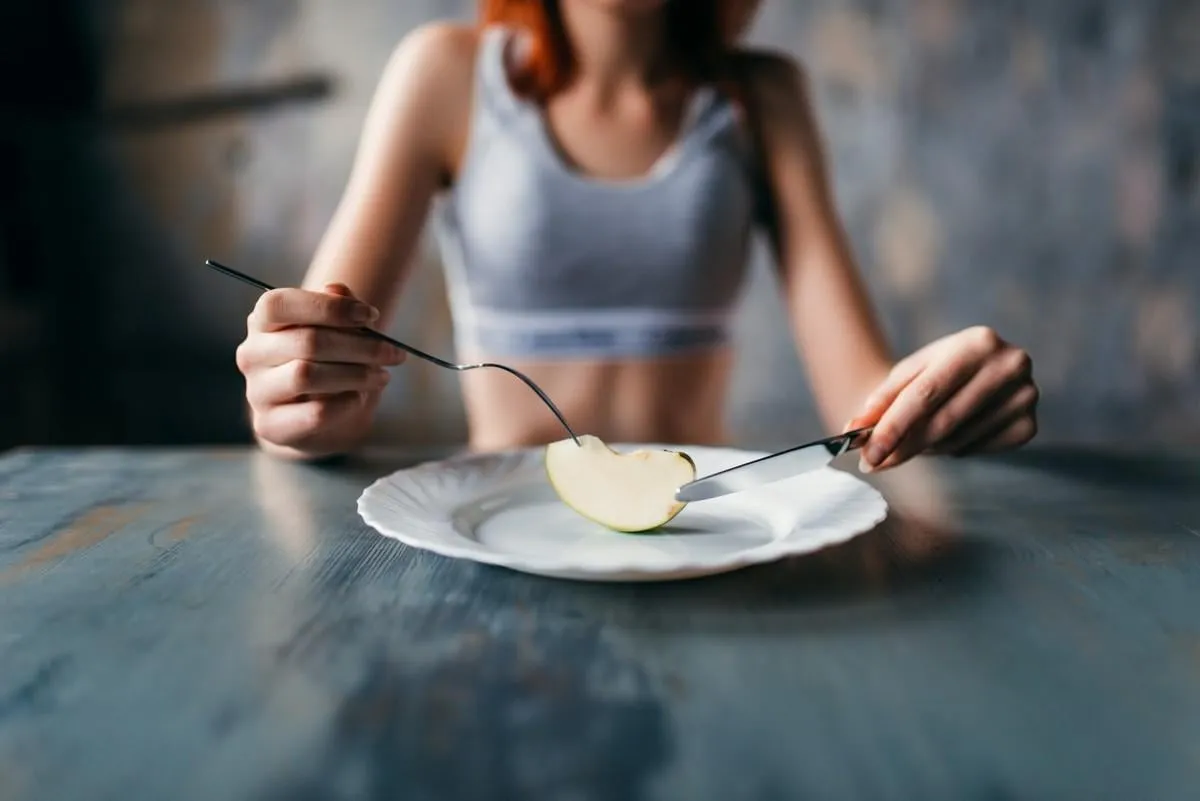 female person against plate with a slice of apple weight loss diet concept