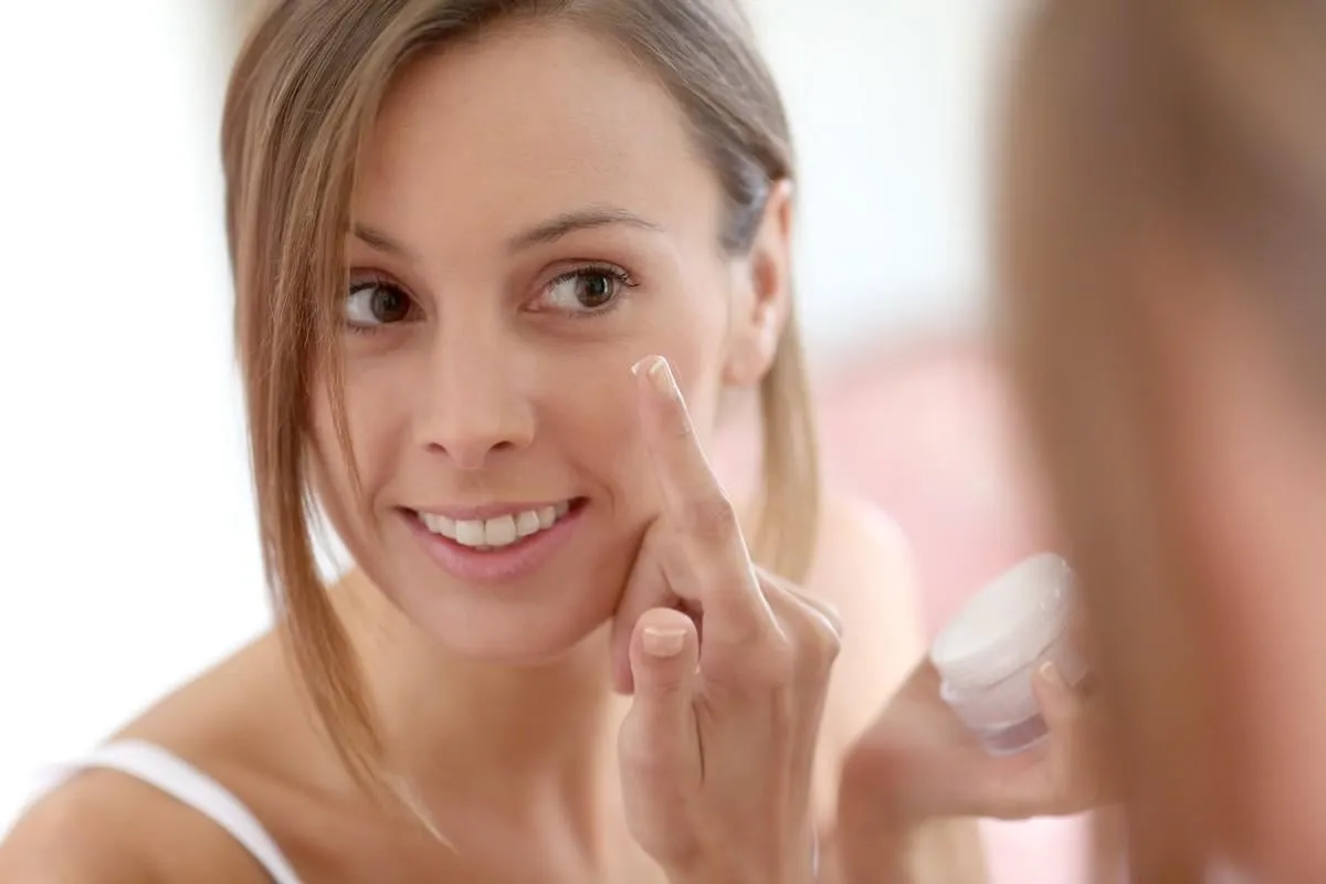 attractive girl putting anti-aging cream on her face