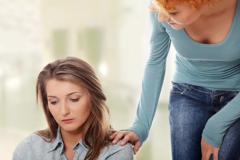 troubled young girl comforted by her friend