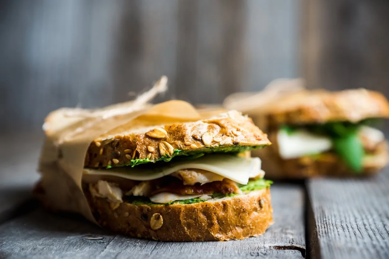 sandwich with cereal bread, chicken, pesto and cheese on the rustic wooden background selective focus shallow depth of field