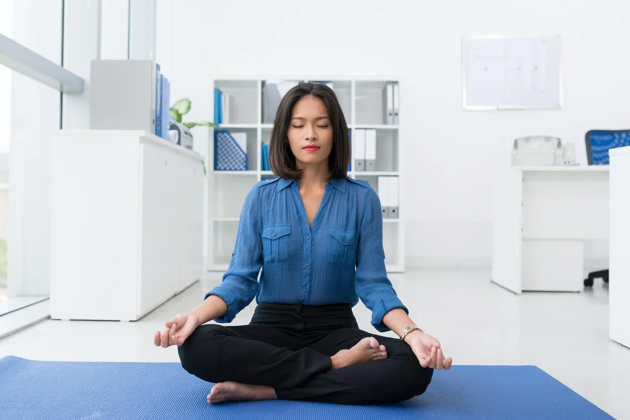 femme d'affaires brune calme pratique d'yoga au bureau