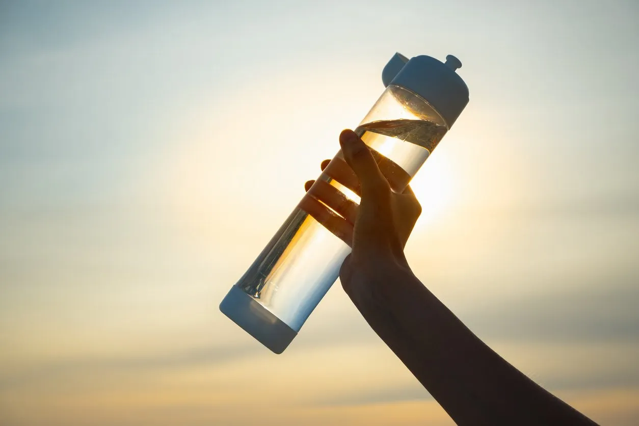 close up of a reusable water bottle in a human hand, concept of thirst, rehydration and decreasing single use plastic