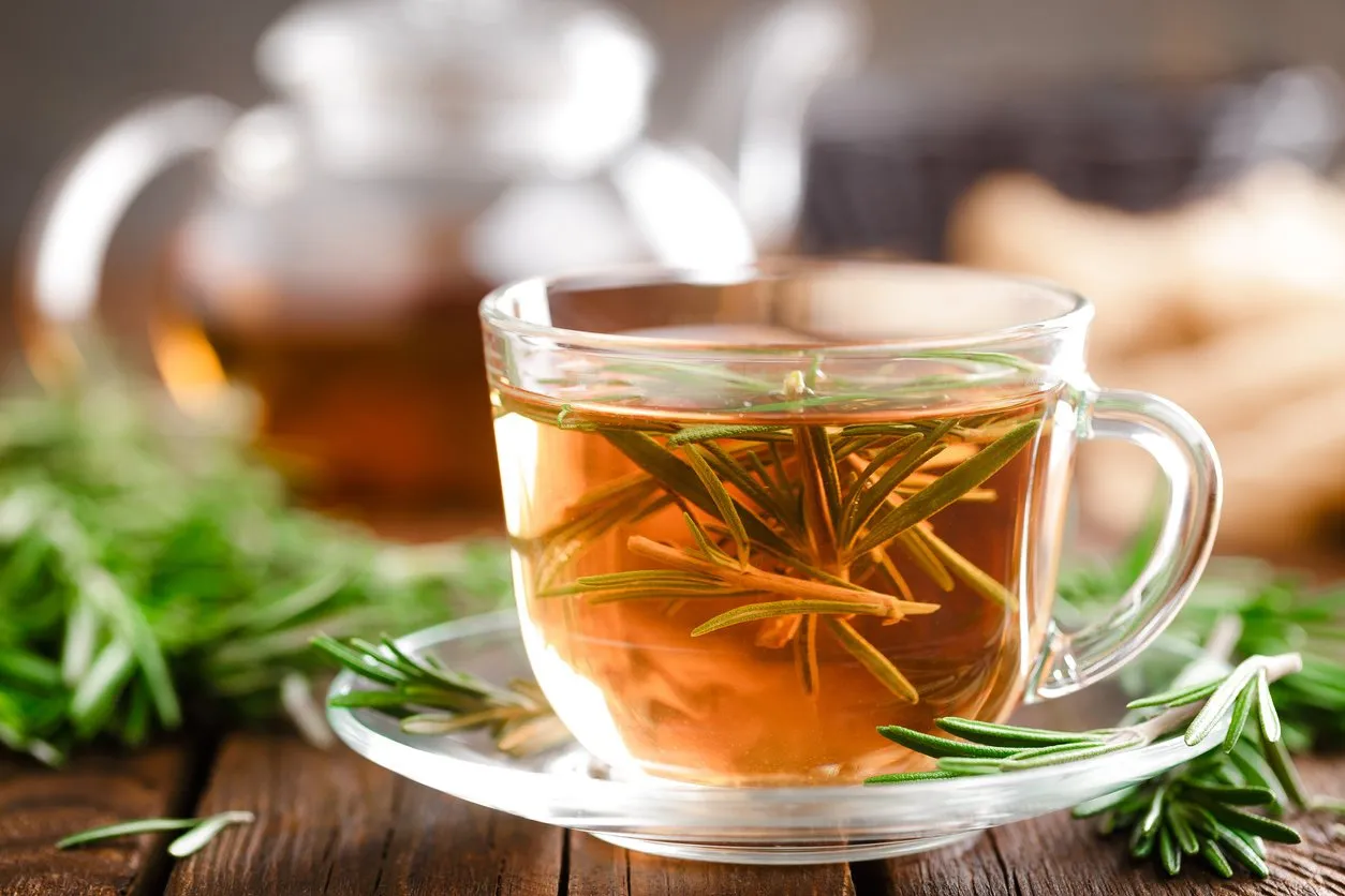 rosemary tea in glass tea cup on rustic wooden table closeup herbal vitamin tea