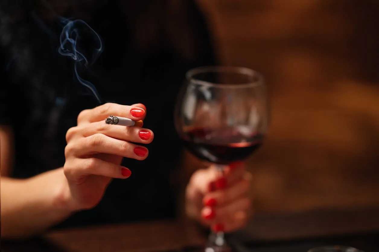 lonely beautiful woman sitting on the bar, smooking cigarette and drink wine