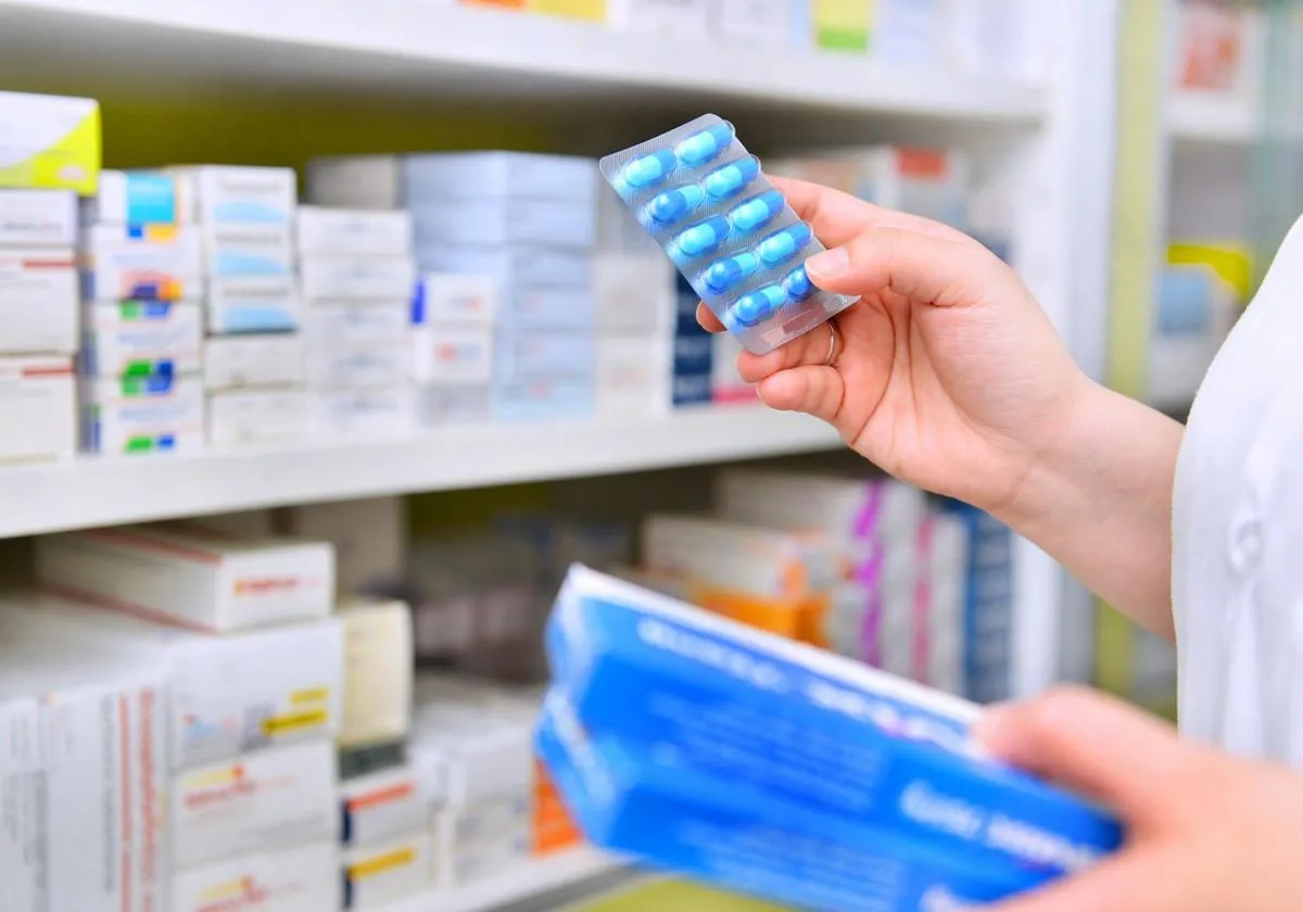 pharmacist holding medicine box and capsule pack in pharmacy drugstore